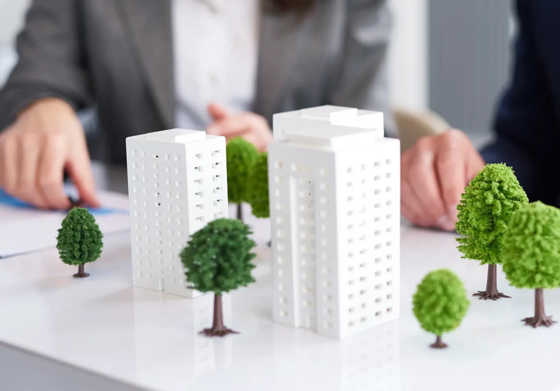 Architectural model of white residential towers and trees on a table